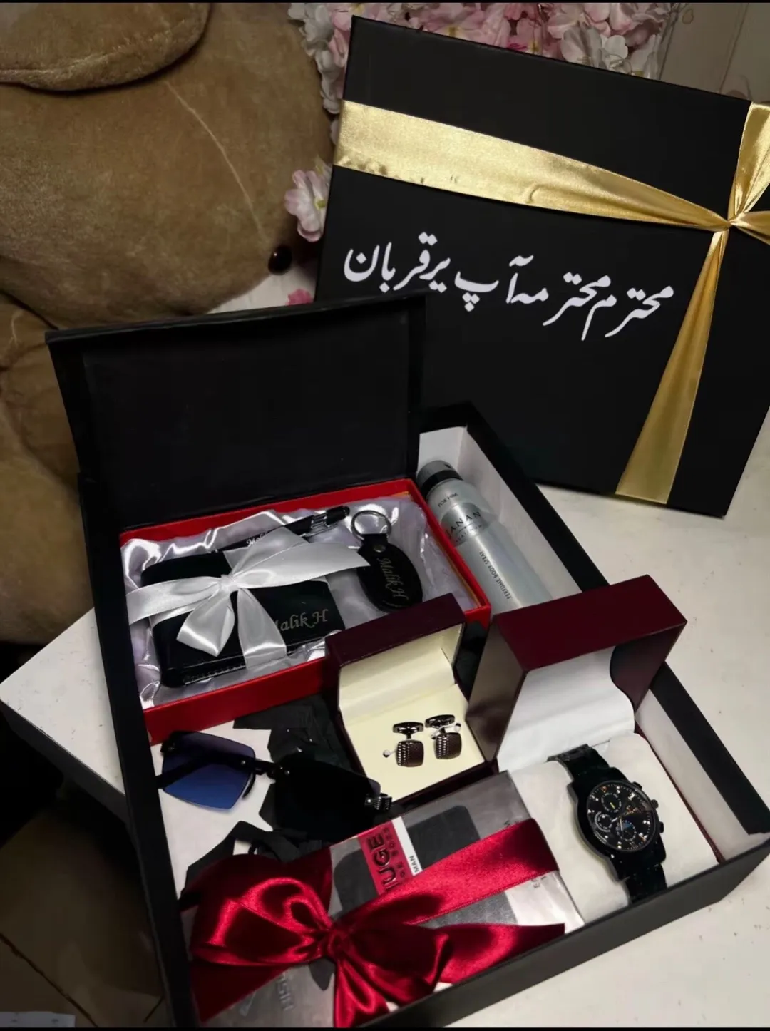 Black gift box containing a watch, wallet, cufflinks, sunglasses, and body spray for men.