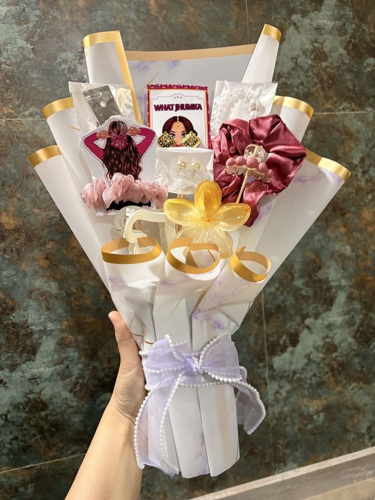 Handheld gift bouquet containing scrunchies, jewelry, and hair accessories wrapped in white decorative paper.