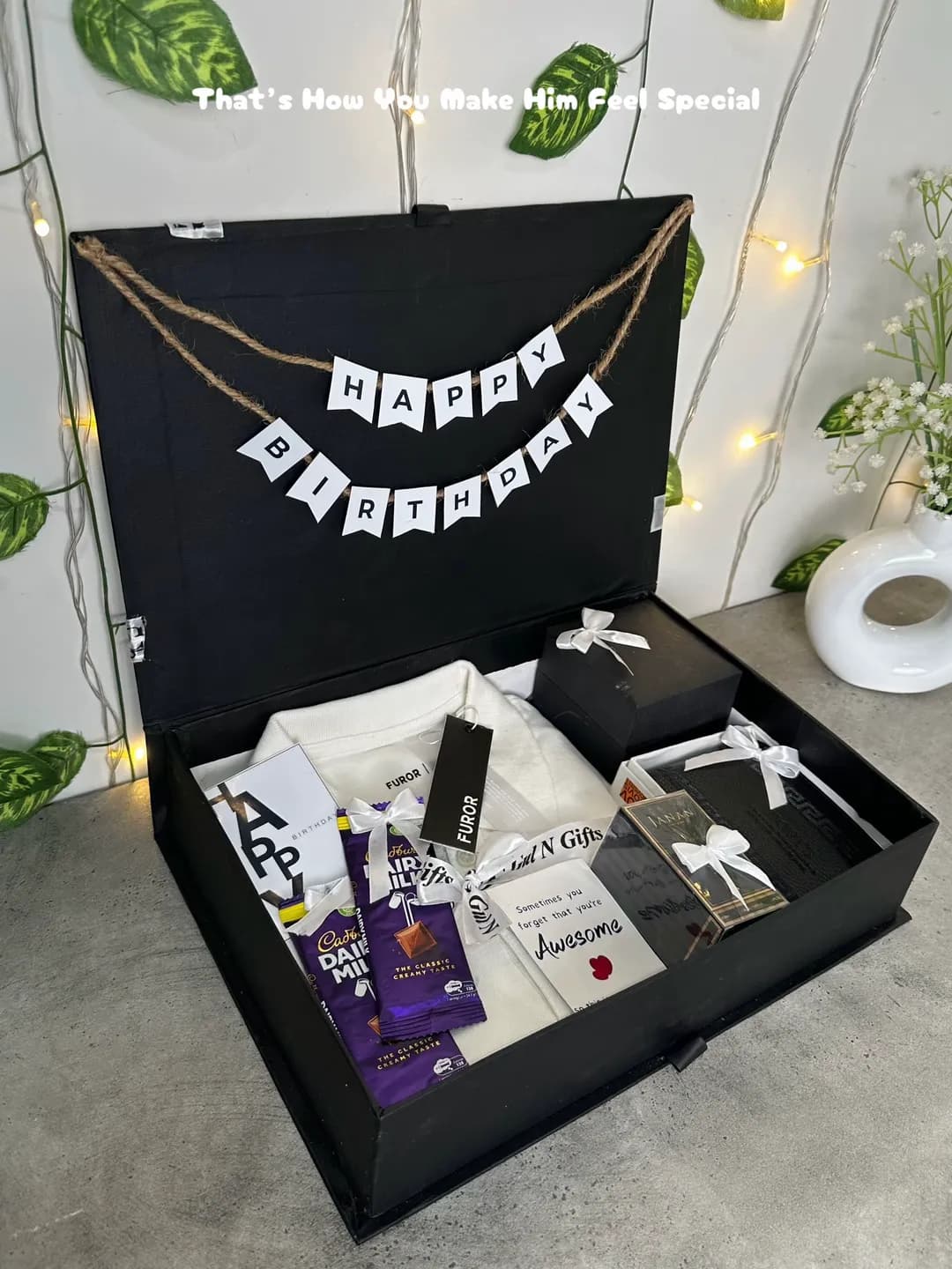Open black gift box with a white shirt, chocolates, perfume, and a Happy Birthday banner.