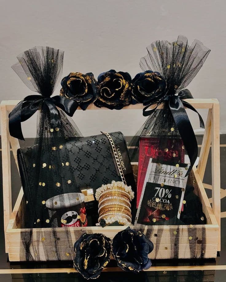 Elegant black and gold gift basket with a clutch, bangles, chocolate, tulle, and roses.